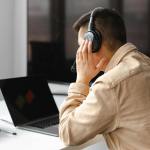man wearing his headphone in front of his laptop
