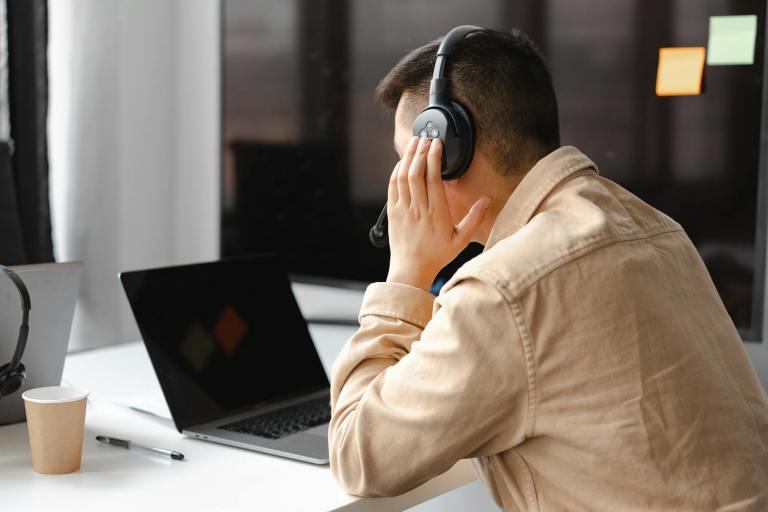 man wearing his headphone in front of his laptop
